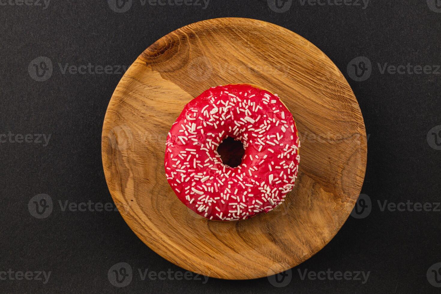 delicious donut that features vibrant red frosting and white sprinkles on top photo