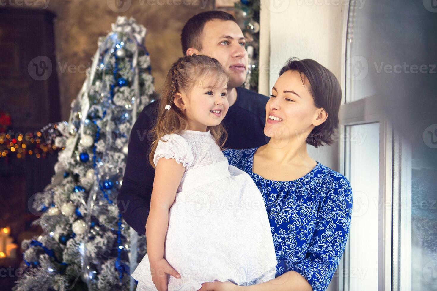 Happy family with little daughter by the Christmas tree photo