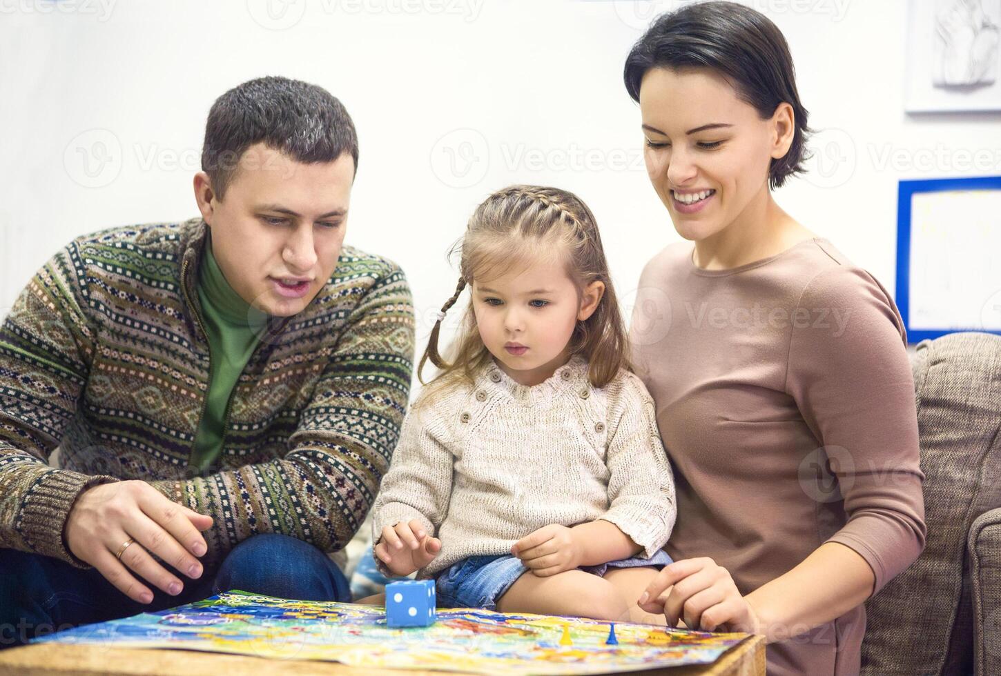 Portrait of happy family with little daughter playing table game photo