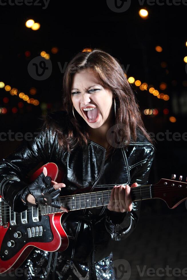 Brunette guitar player girl in the night photo