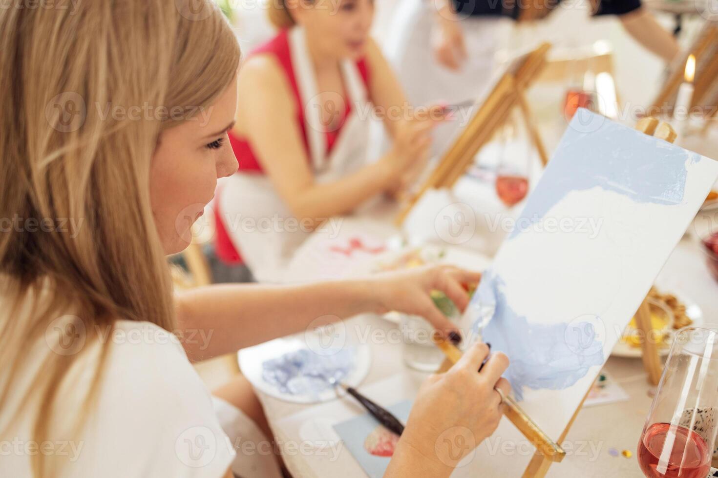 Close-up of canvas on easel and hand with spatula. Young artist paints picture at table. photo