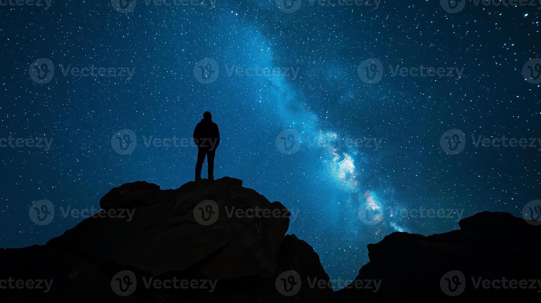 Silhouette of a figure gazing at the stars beneath a dazzling display of northern lights photo