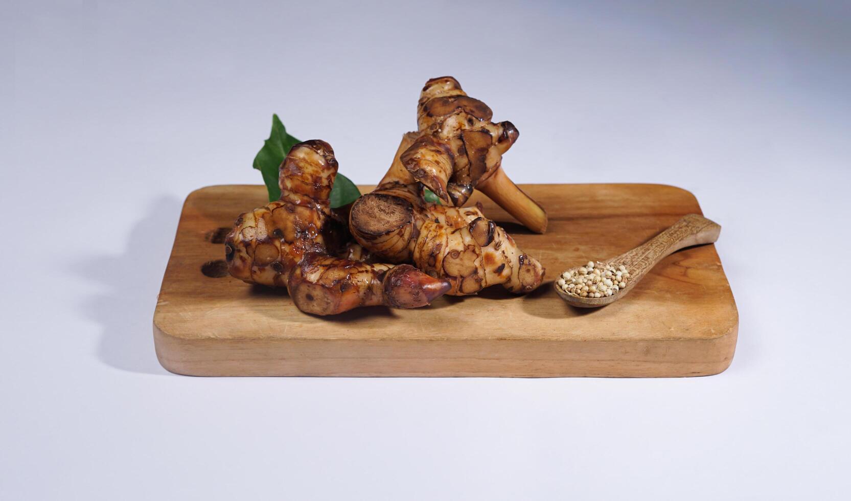 Fresh galangal root on wooden bowl isolated on white background. Galangal root are used in tradtional asian cuisines. photo