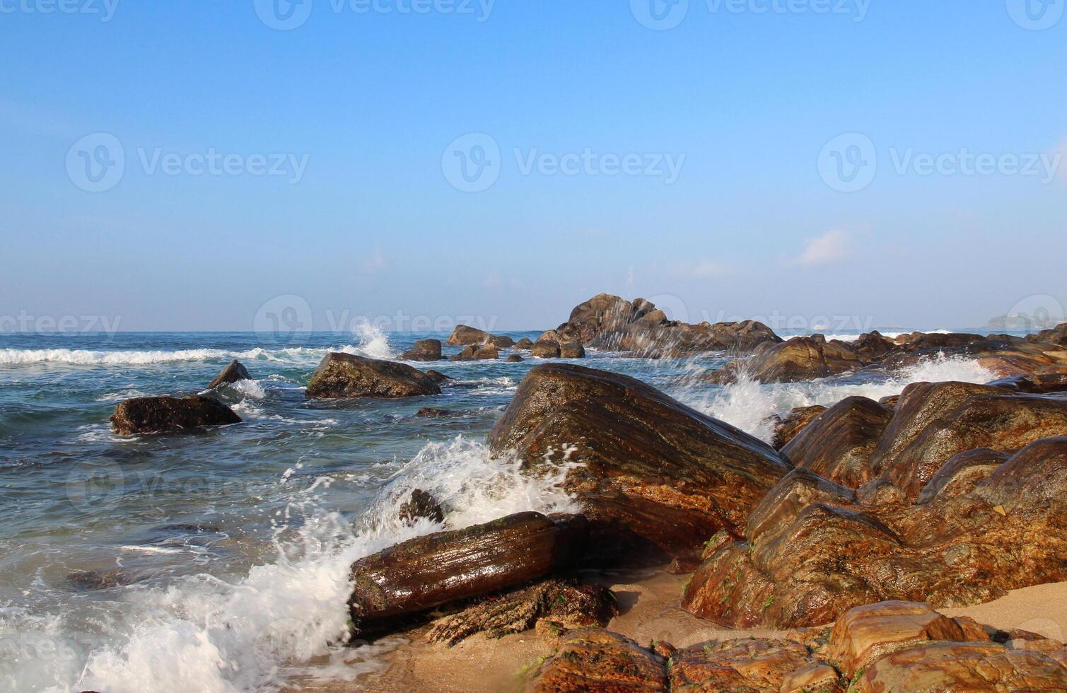 Picturesque rocky coast with ocean waves crashing on rocks on a sunny summer day. Perfect for nature themes. Travel background, card photo