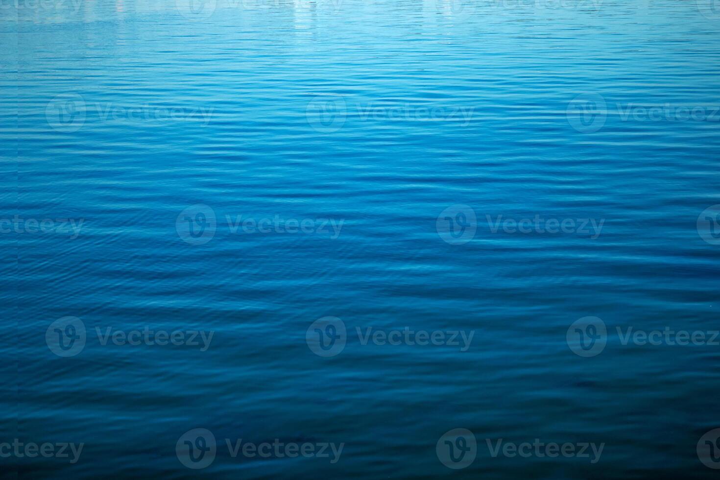 Water ripple texture. Blue background of the water surface. Wavy water surface during the day in bright sunlight. photo