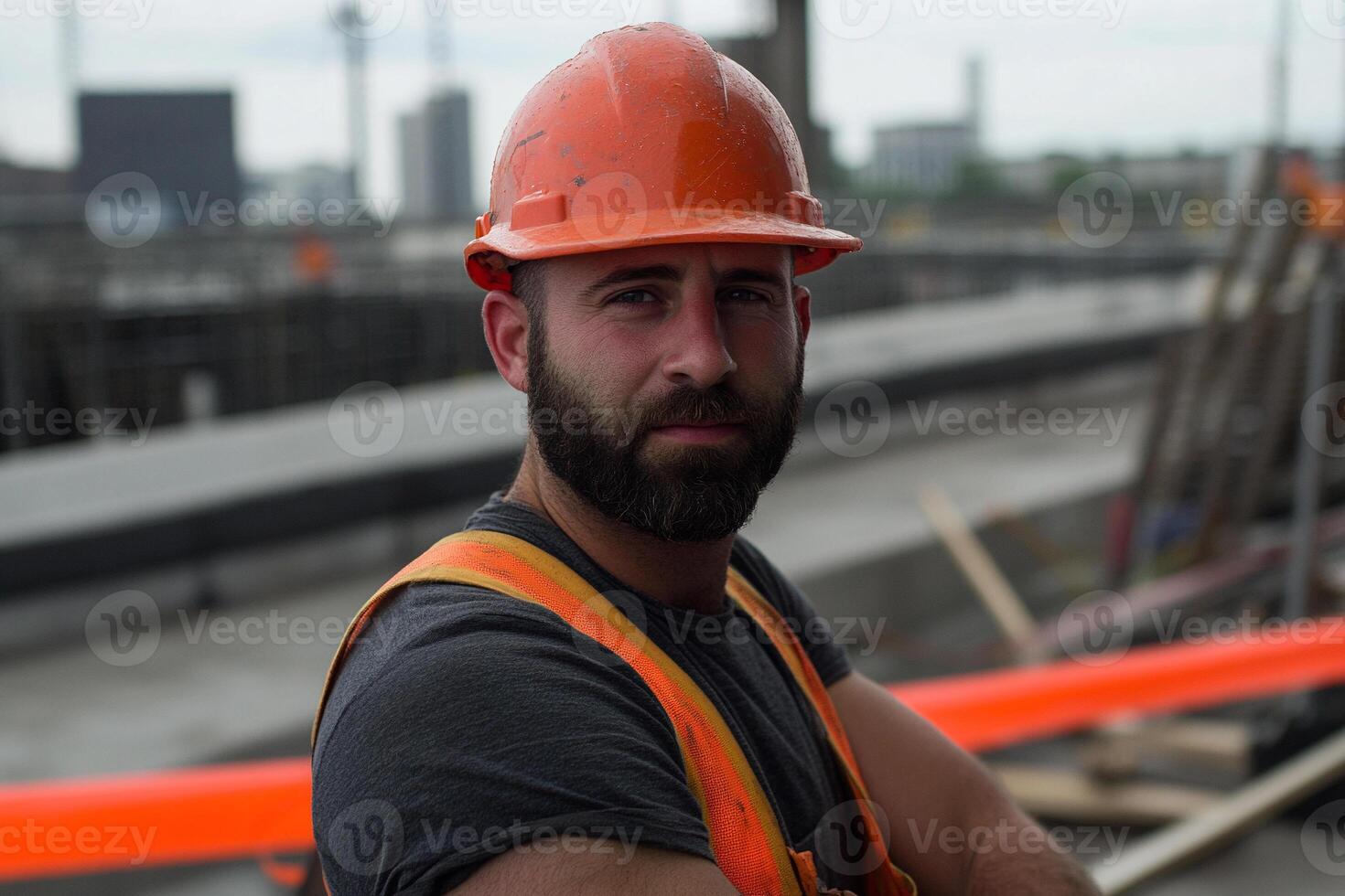 A man with a beard and orange hard hat standing in front of a construction site photo