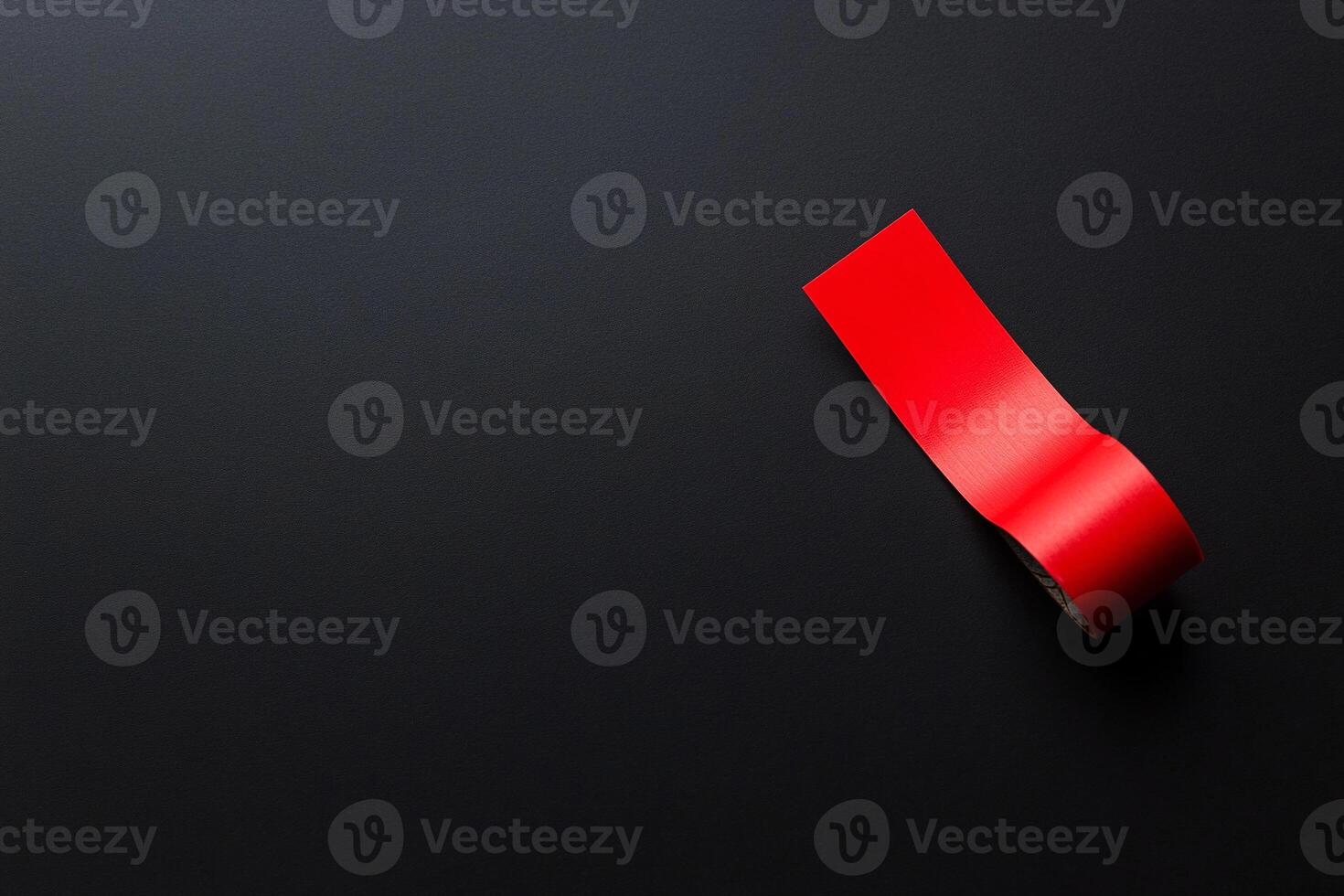 A red tape is sitting on top of a black surface photo