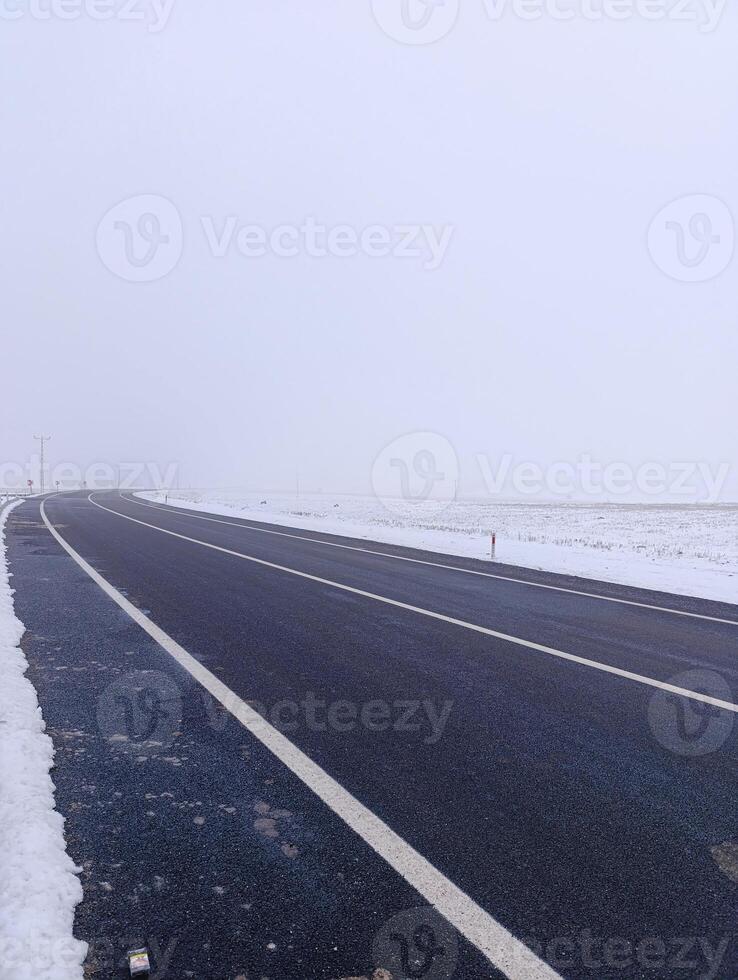 A highway with snow falling around it. Foggy and cold weather. photo