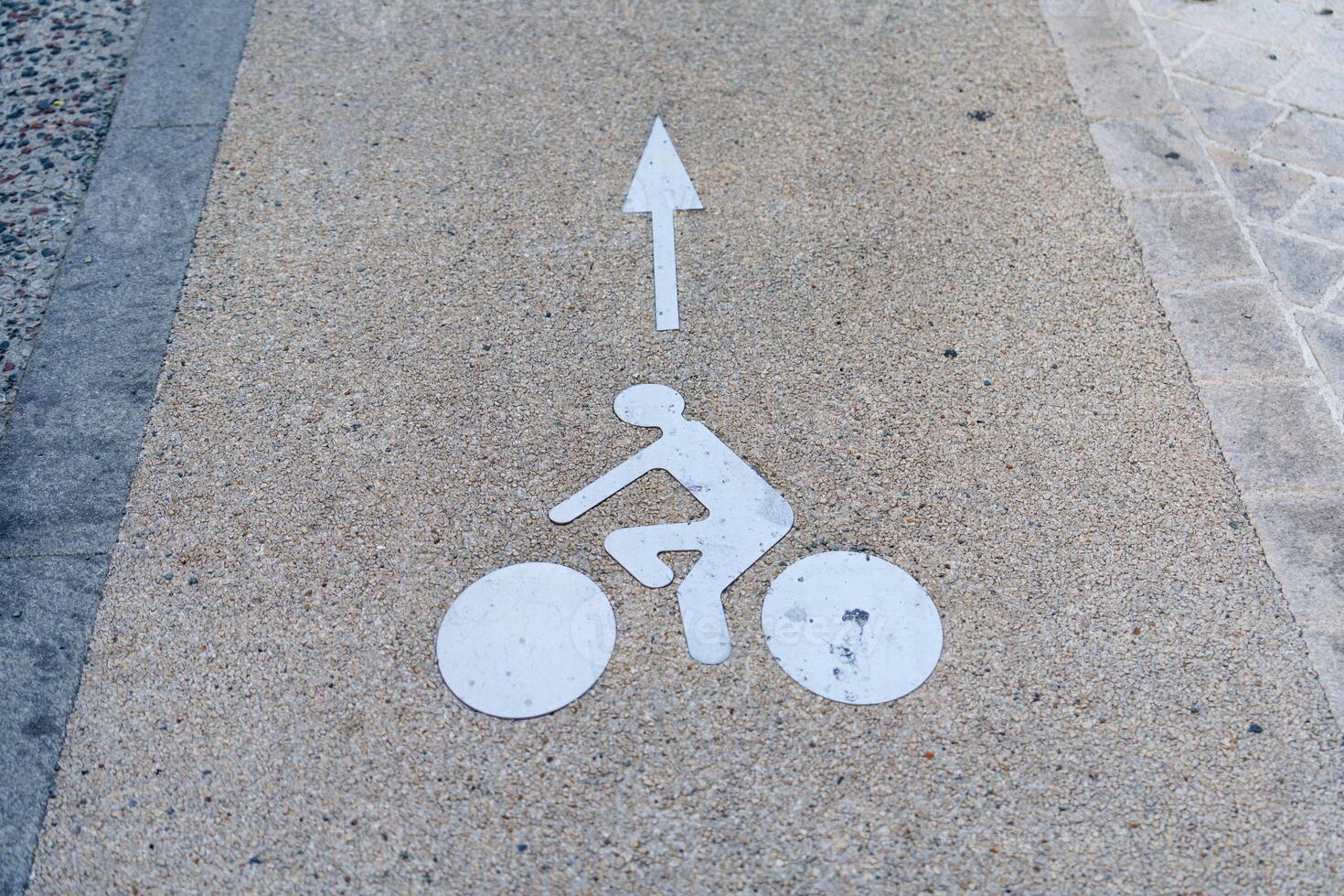 A white arrow pointing to a bicycle on a sidewalk photo