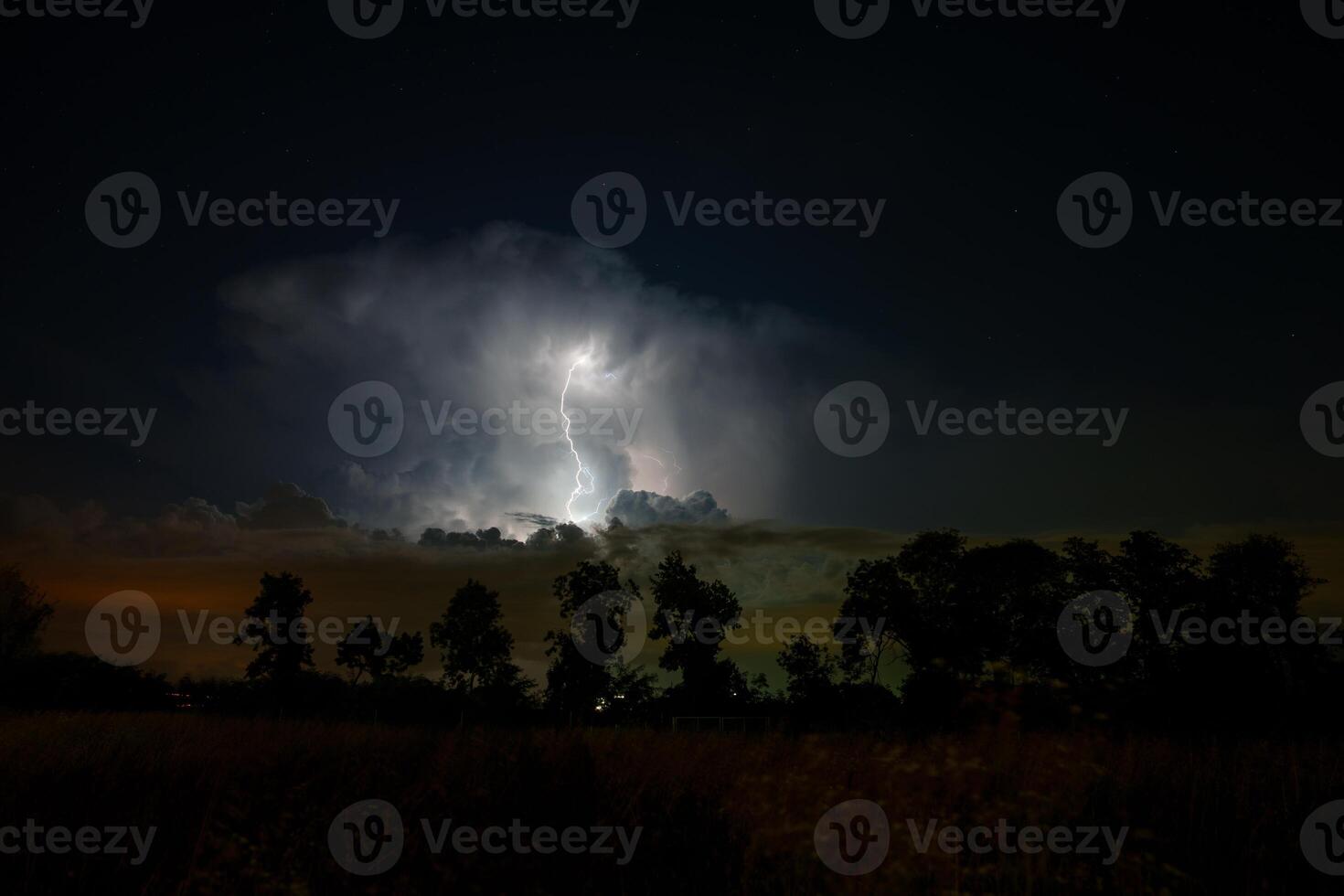 A lightning bolt is seen in the sky over a field photo