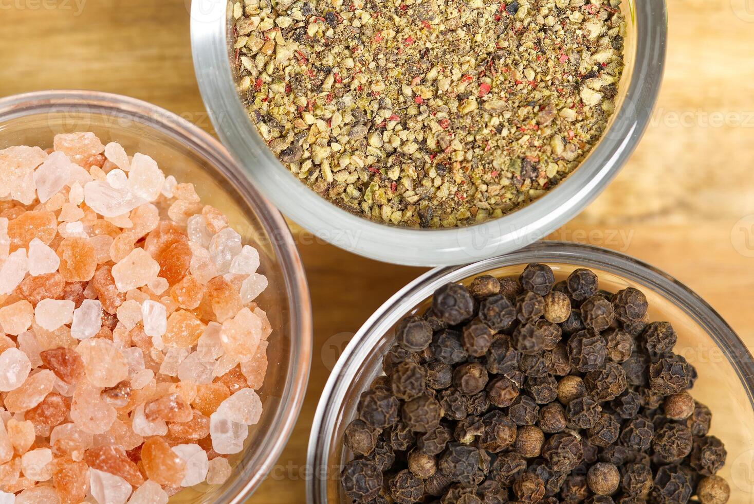 Three bowls of spices and salt on a wooden table photo