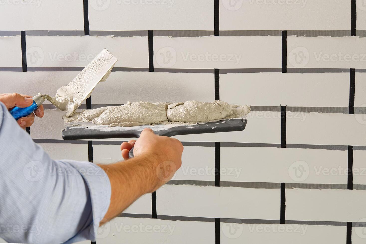 A man is using a knife to cut a tile photo