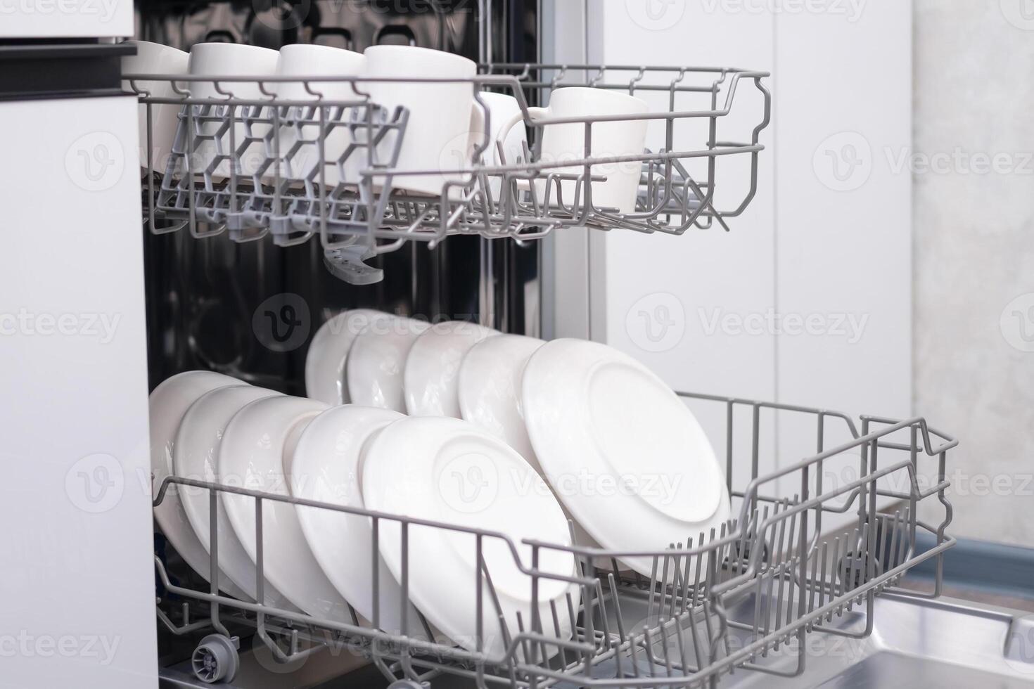 The door of the built-in dishwasher is open, close-up of white plates photo