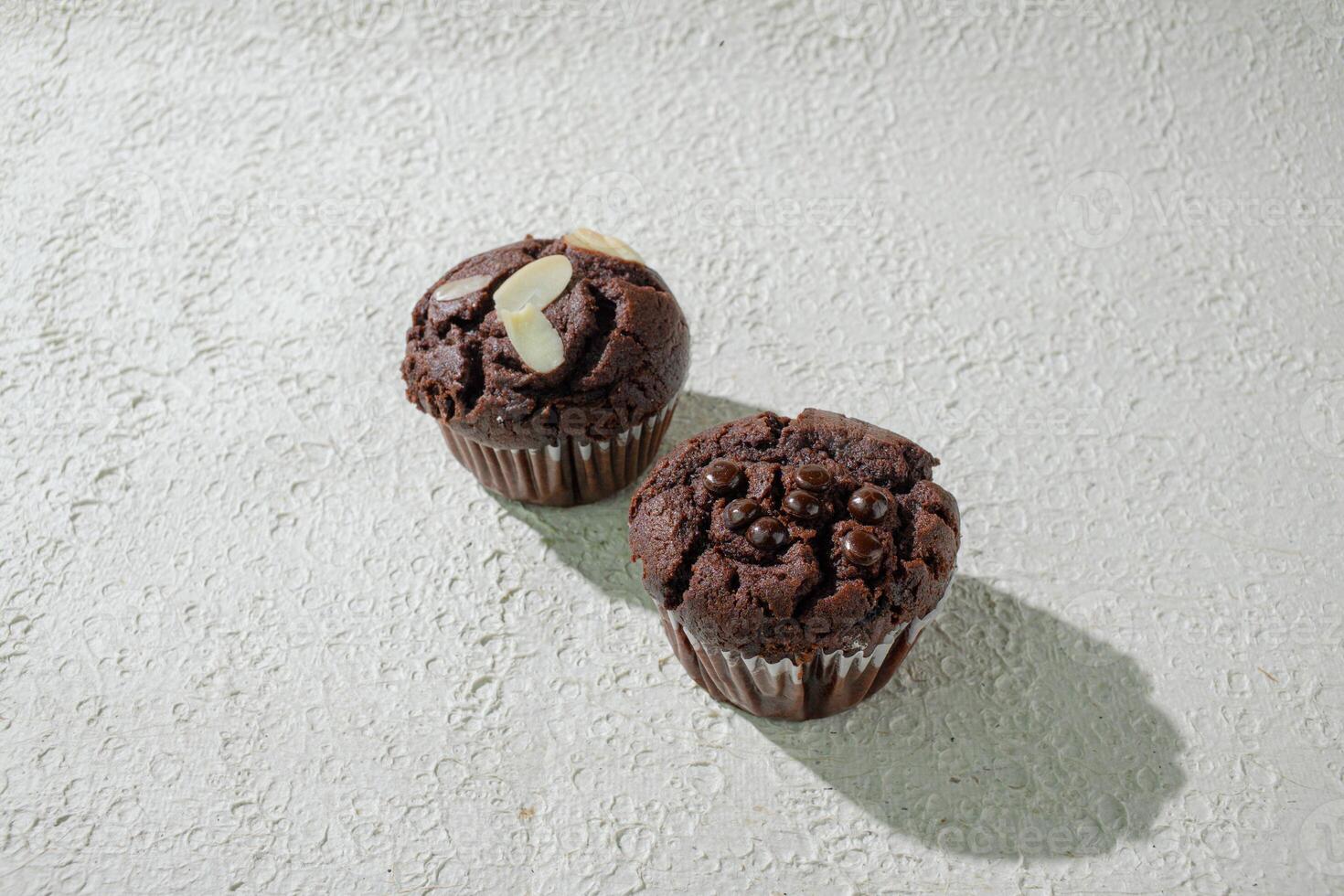 two chocolate muffins sitting on a white surface photo