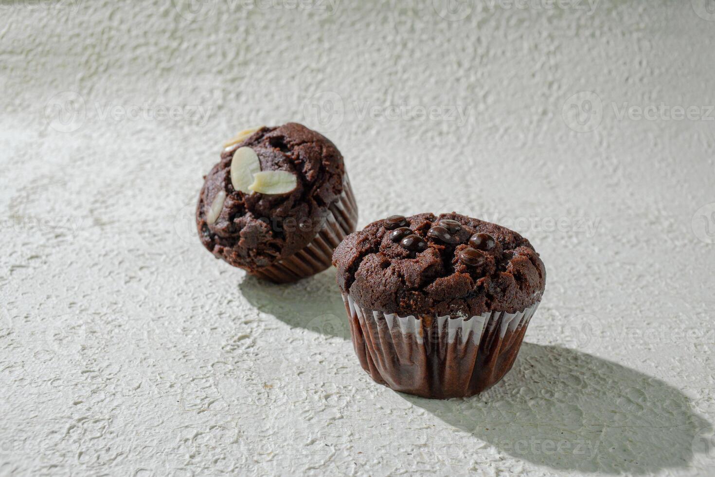 two chocolate muffins sitting on a table photo