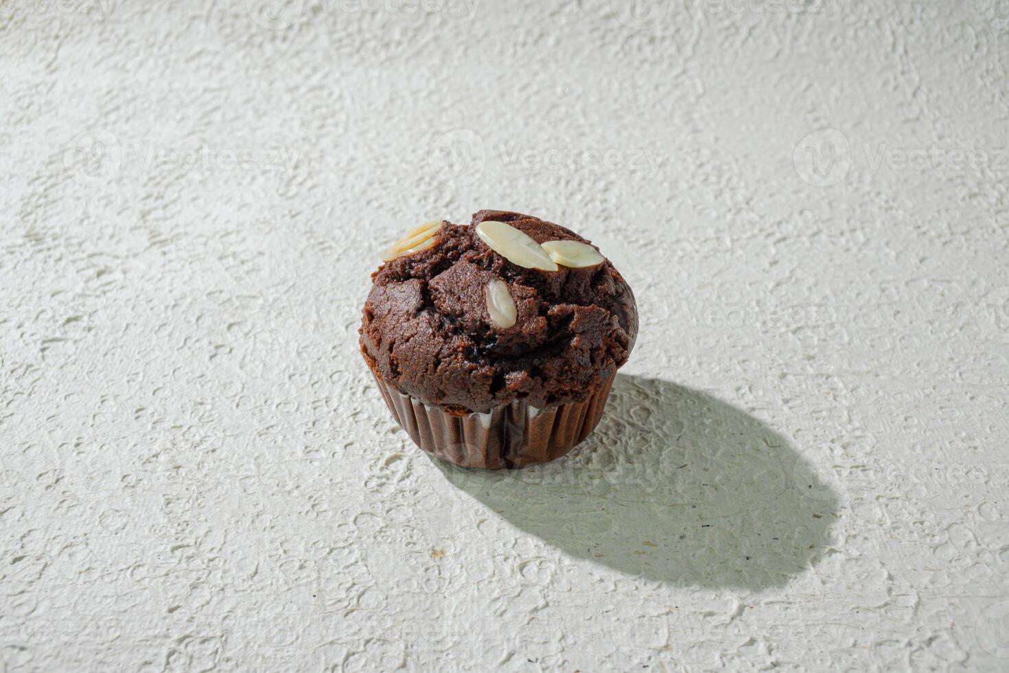 a chocolate muffin sitting on a white surface photo
