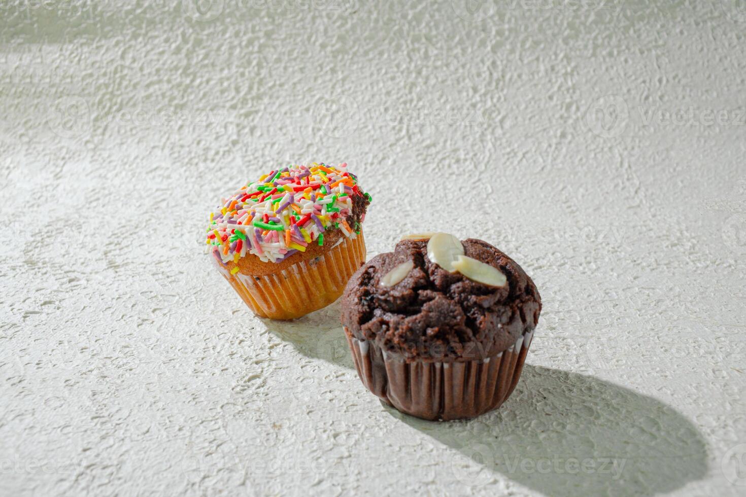 two cupcakes sitting on a table background photo