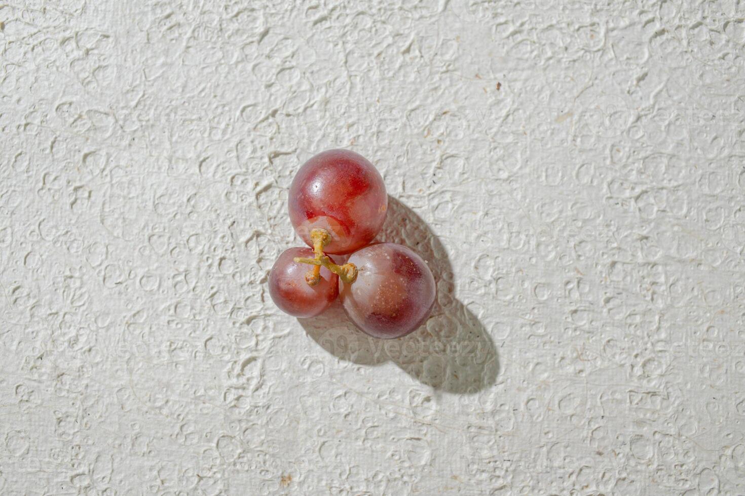a close up of a bunch of grapes on a white wall photo