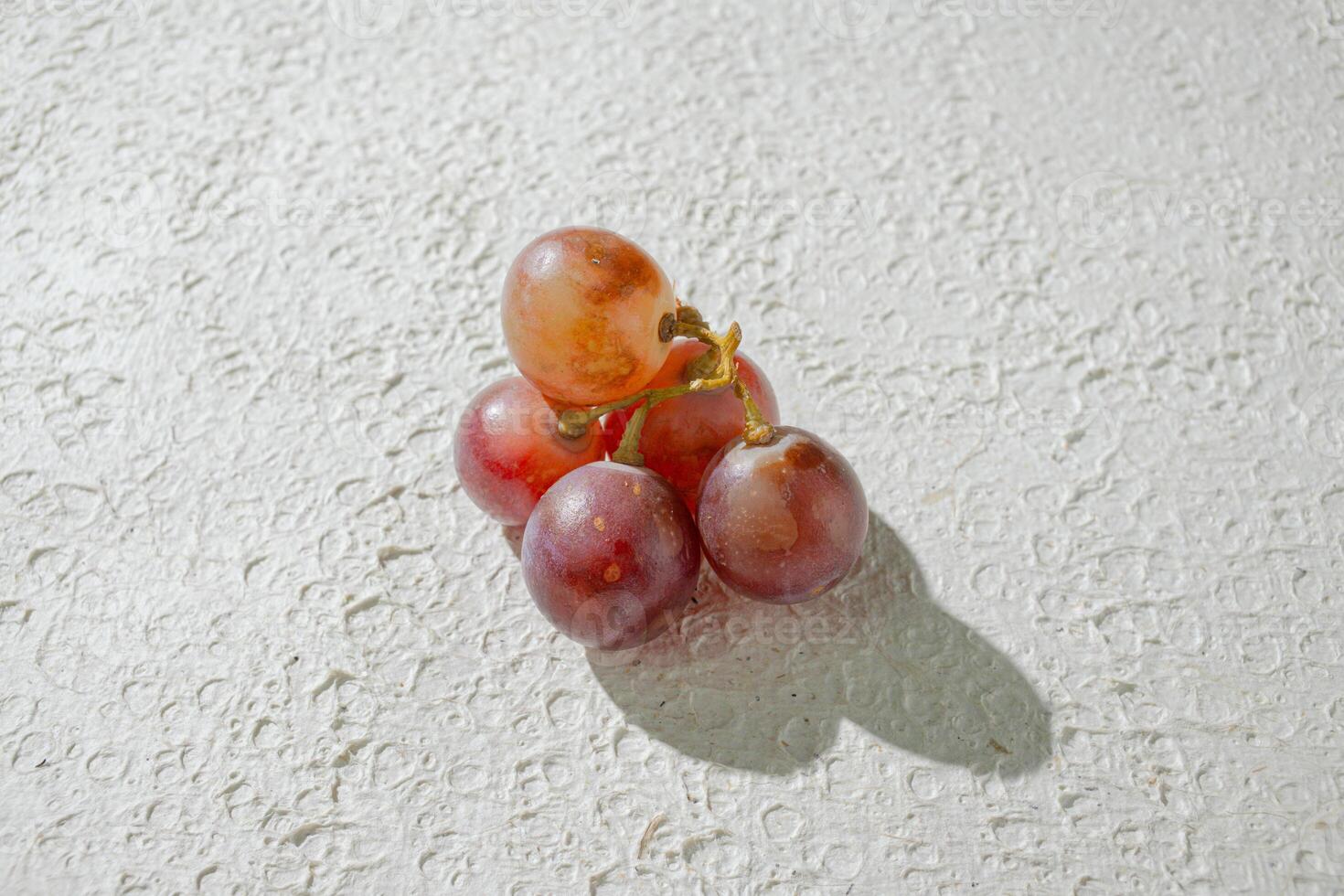 a bunch of grapes on a white surface background photo