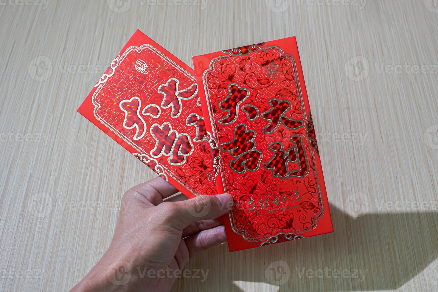 hand holding traditional red angpao used for gifting money during Chinese New Year, symbolizing good luck and prosperity photo