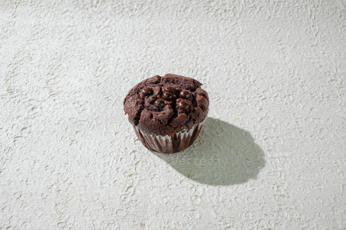a chocolate muffin sitting on a white surface background photo