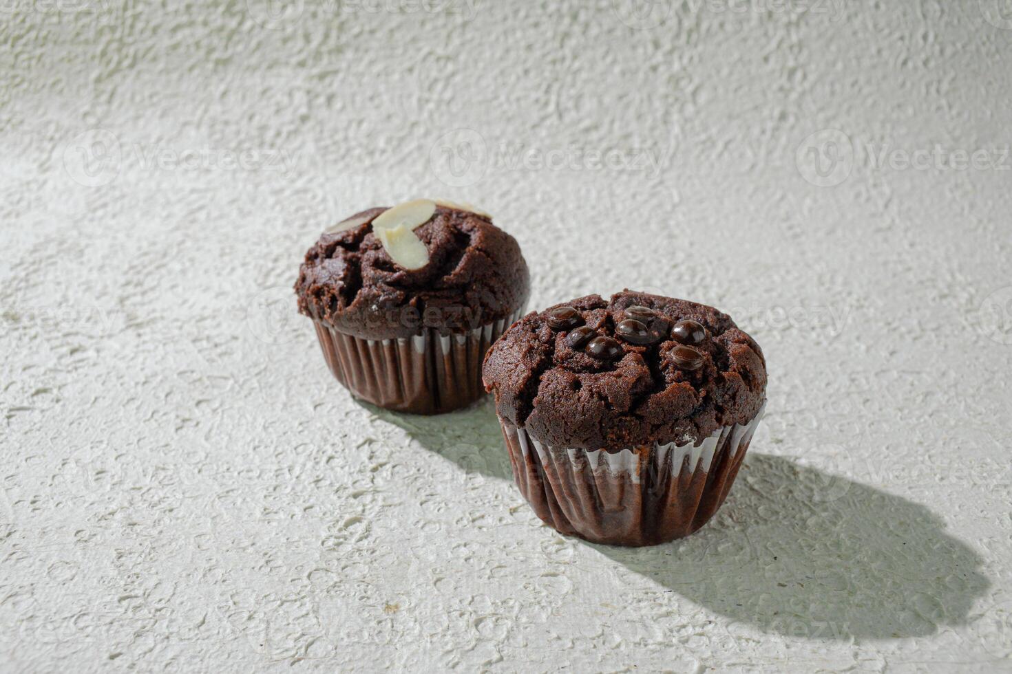 two chocolate muffins sitting on a white background photo