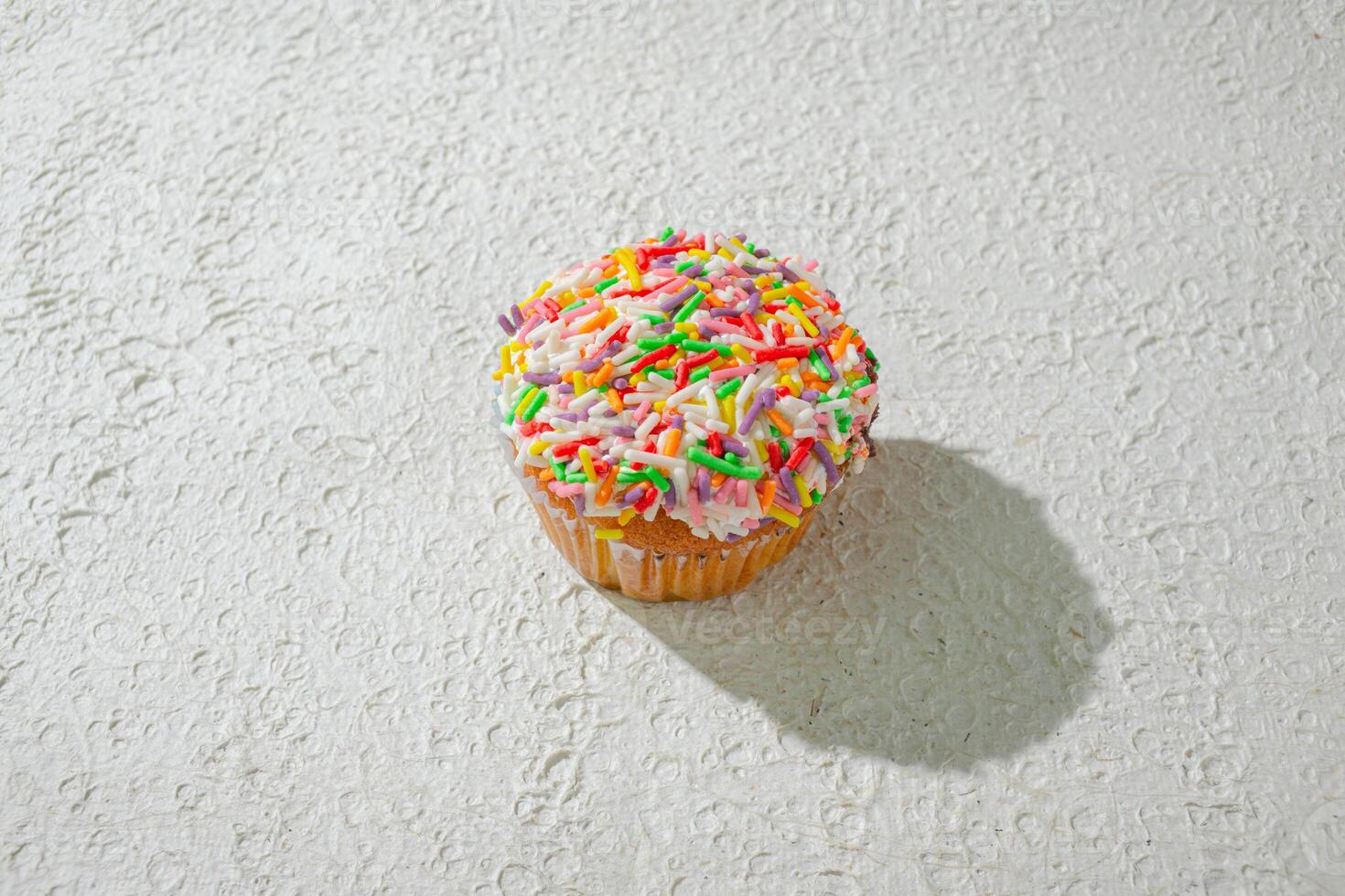 a cupcake with sprinkles on top of a white wall photo