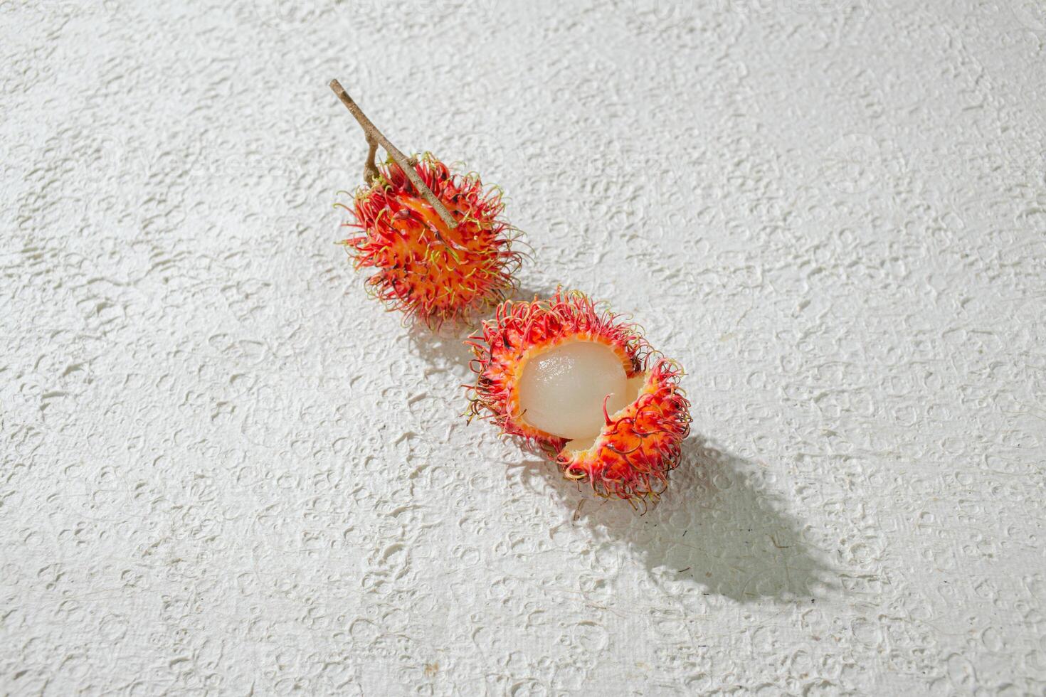 Fresh peeled two red rambutan on a textured white background, perfect as a digital asset for design projects, posters, advertisements, or creative media photo