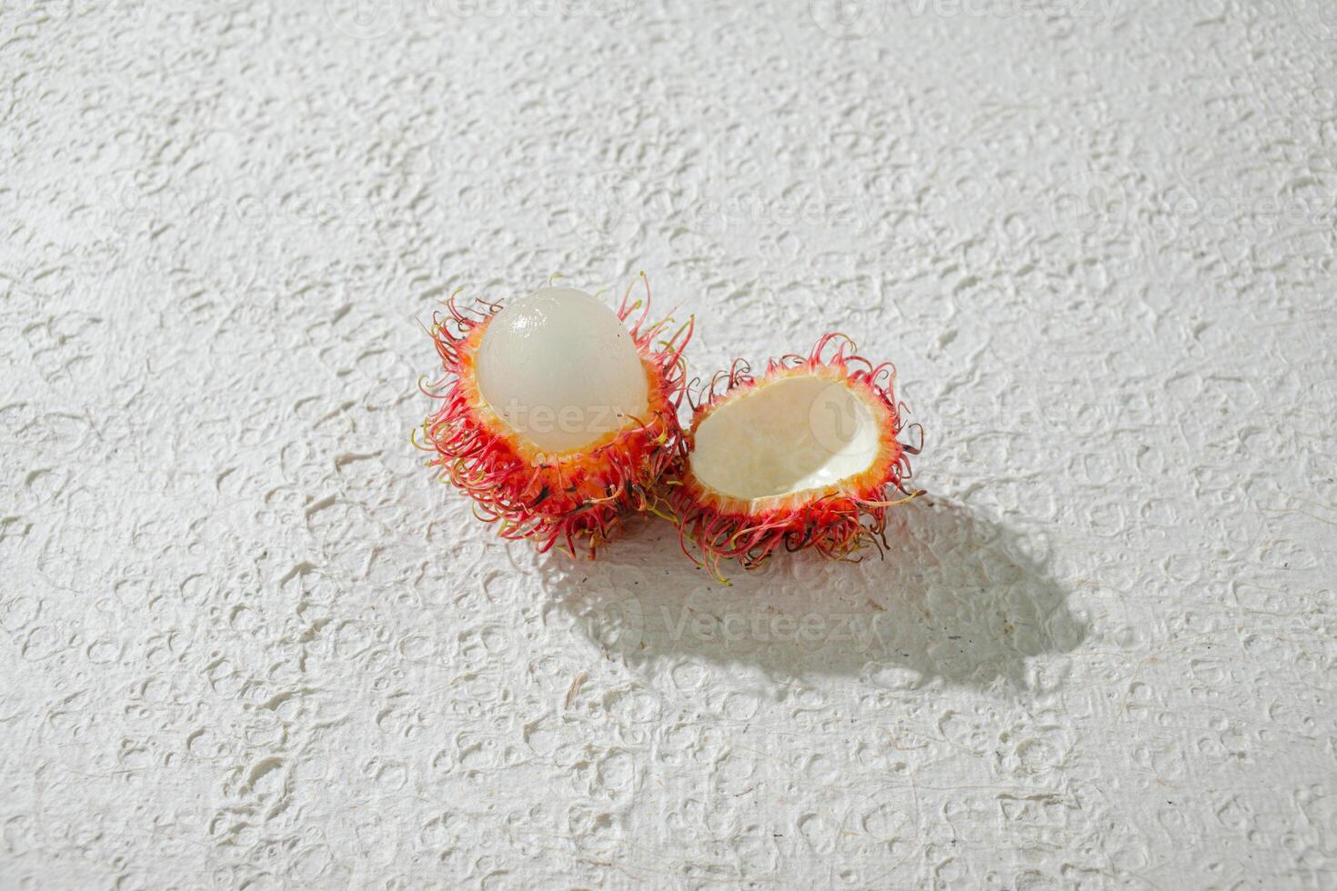 Fresh peeled one red rambutan on a textured white background, perfect as a digital asset for design projects, posters, advertisements, or creative media photo