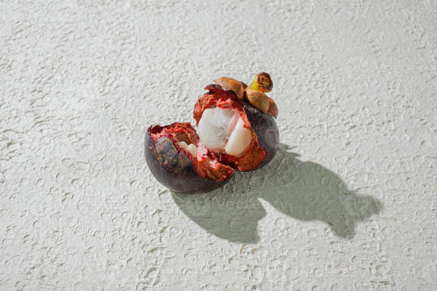 a mangosteen fruit with a cut open on it. isolated on white texture background photo