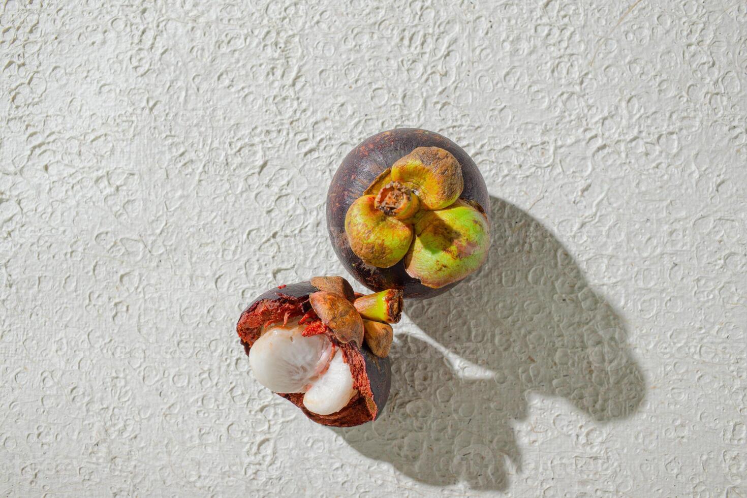 a mangosteen fruit with a seed inside of it. isolated on white texture background photo