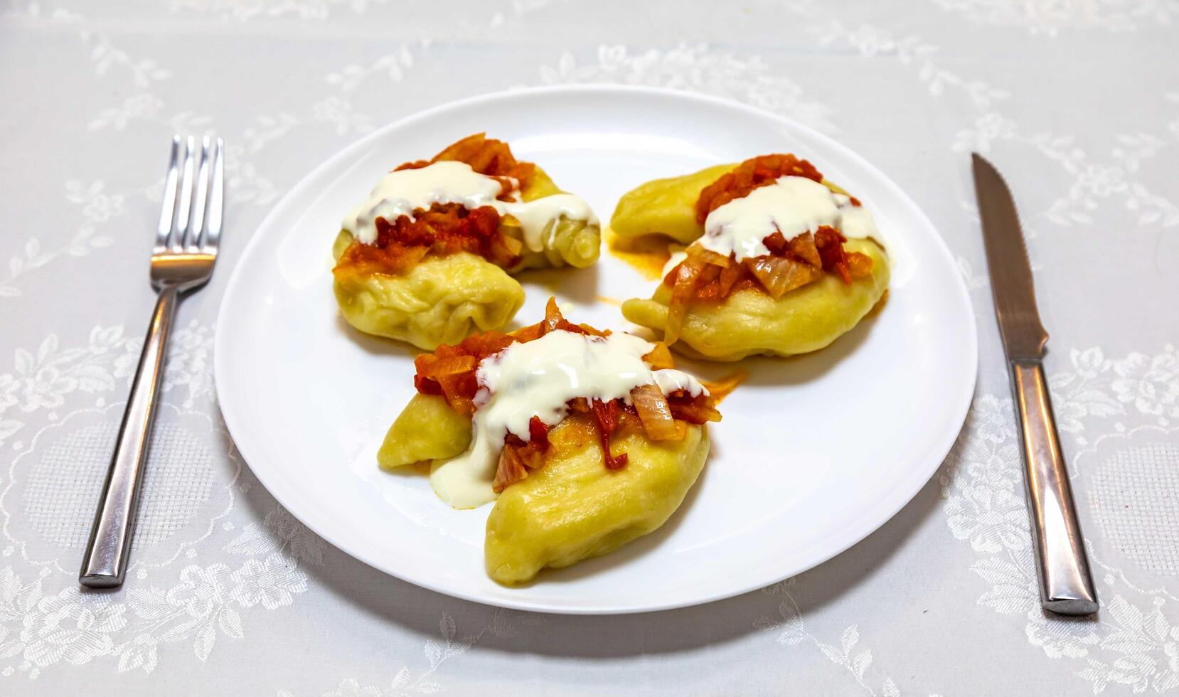 Classic Ukrainian food, perohe or verenekes of sauce andi stuffed with potatoes and cottage cheese and cooked, served with different typ salted and sour cream photo
