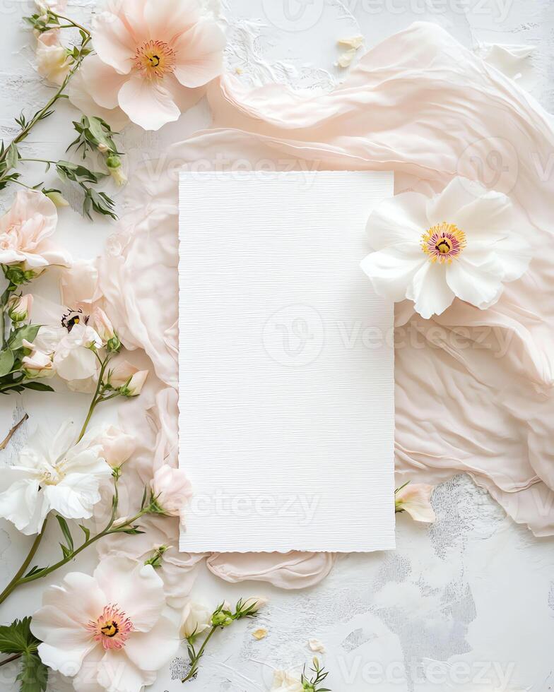 composition with delicate pink flowers arranged around a blank card on a white background, invitation to a celebration photo