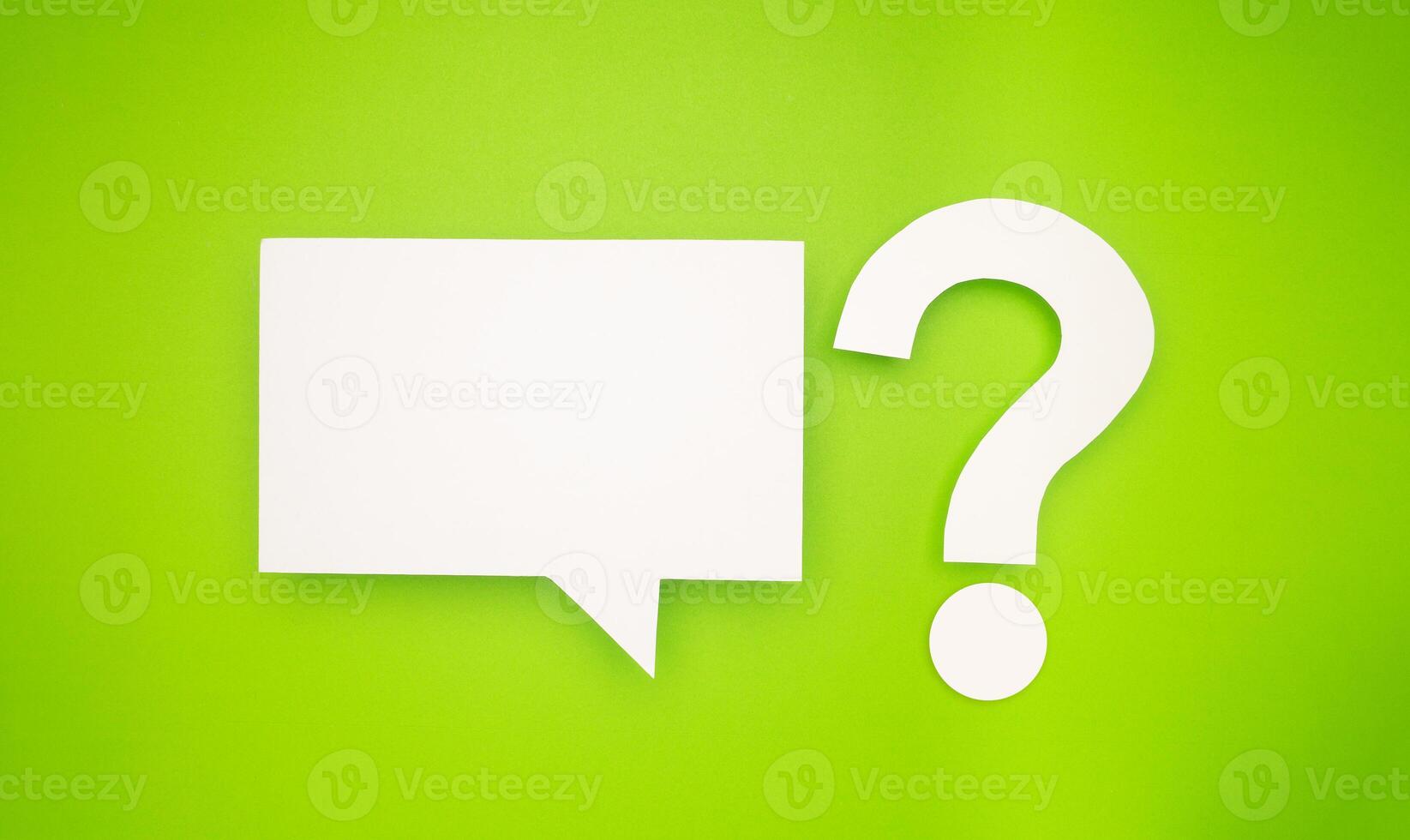 A white speech bubble and question mark symbol are on a light green background photo