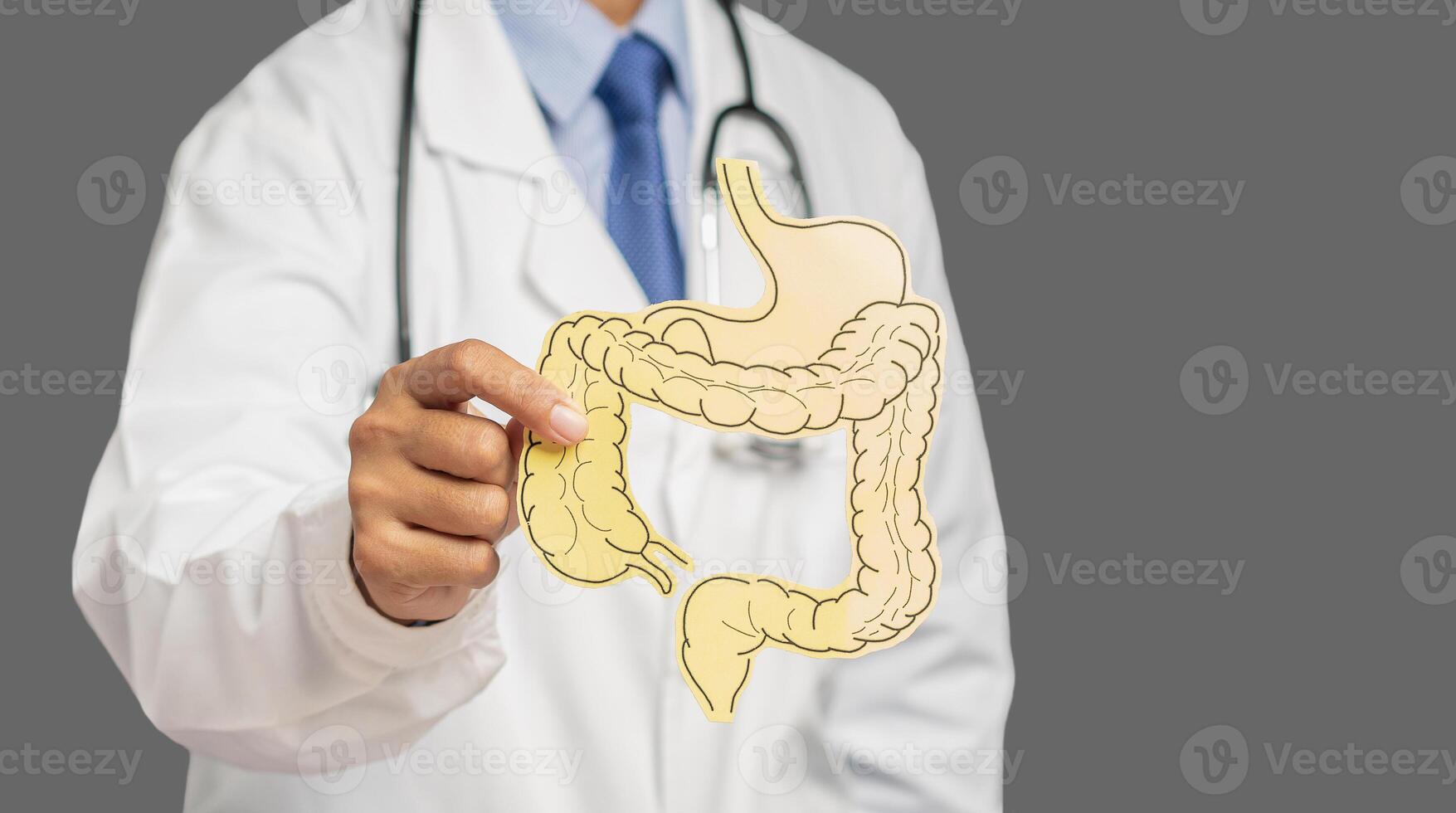A doctor is holding a colon symbol while standing on a gray background photo