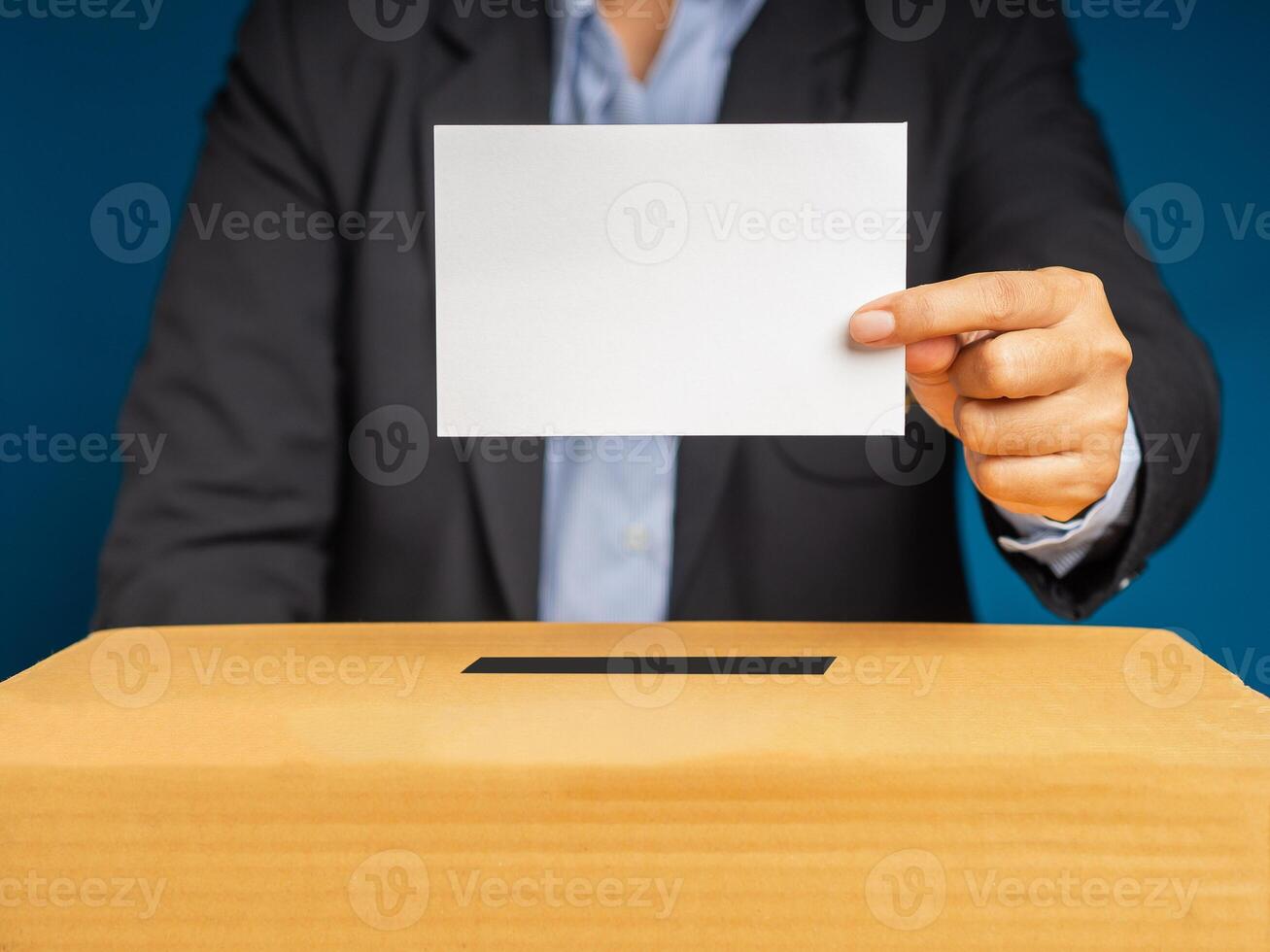 Hands voter holding ballot paper putting into the voting box at place election with a gray background photo