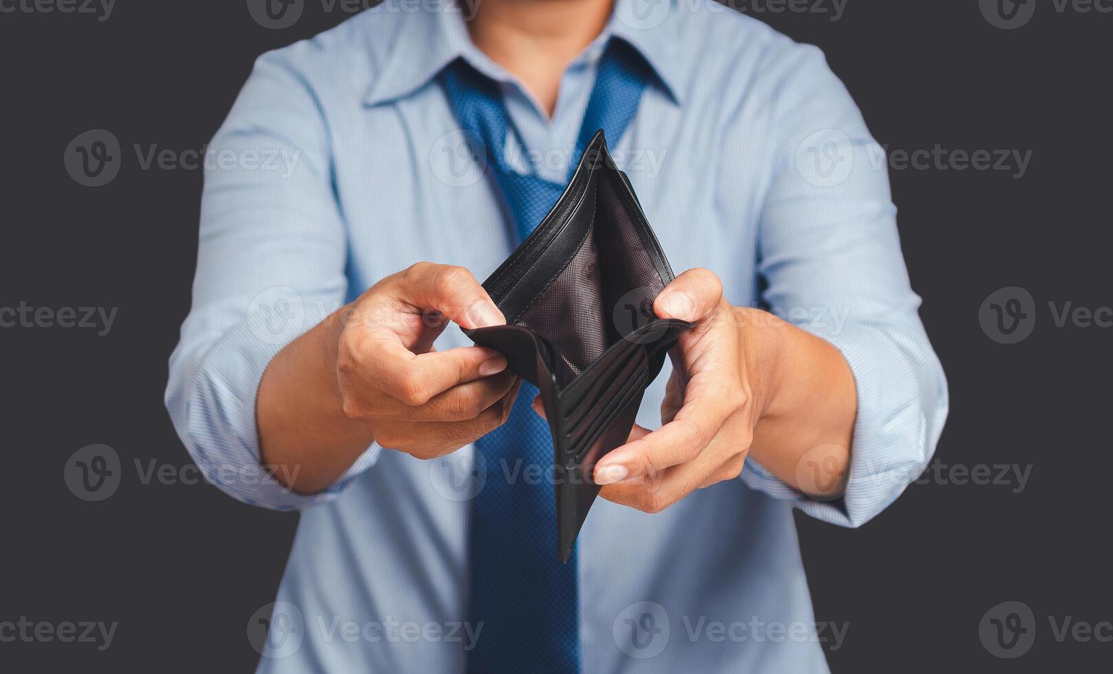 A man in blue shirt hands opens an empty wallet while standing on a gray background photo