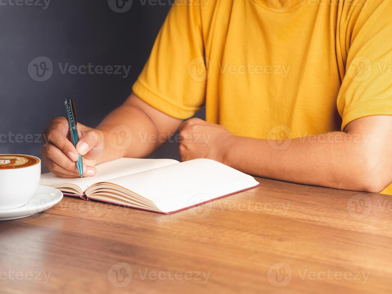 Close-up of hand holding a pen writing on a notebook on the desk photo