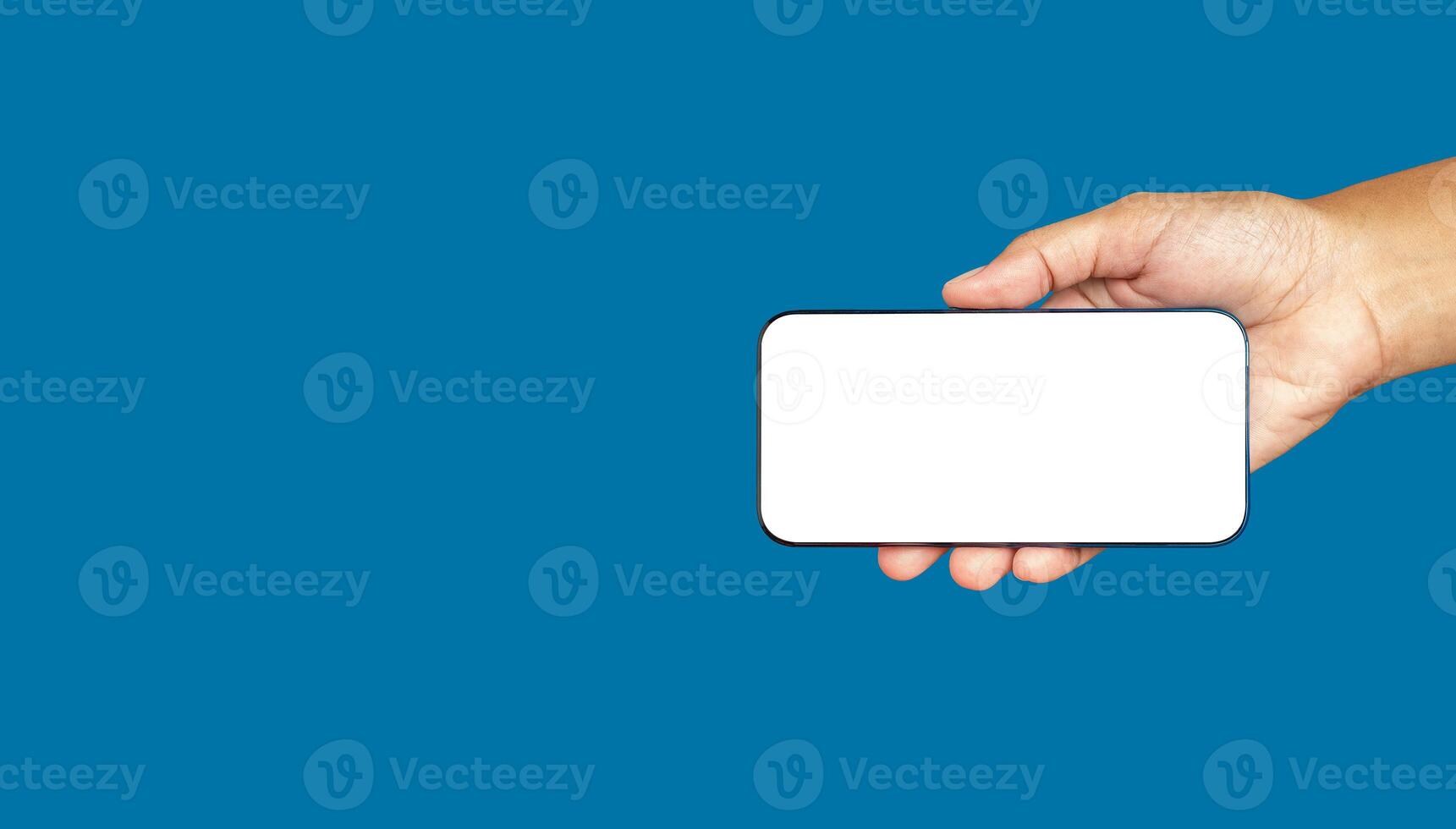Hand holding a white blank screen smartphone against a blue background photo