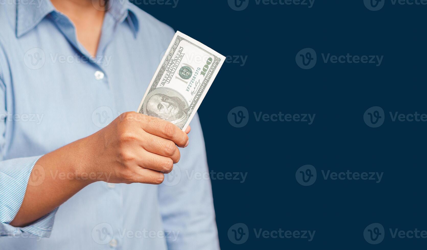Close-up of hand holding US dollars banknotes while standing on a blue background photo