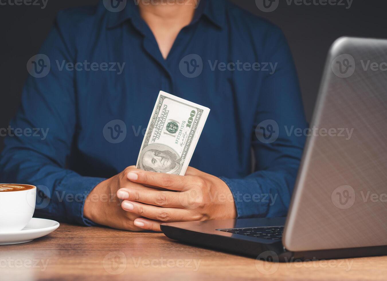Close-up of hands holding US dollar banknotes while sitting at the table photo
