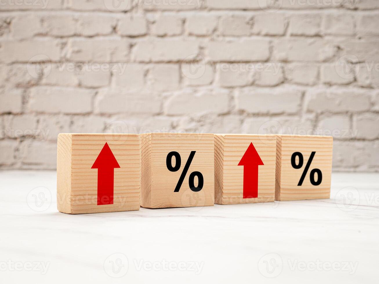 Wooden cubes with red arrows up and percent symbols on a marble floor with white brick background photo