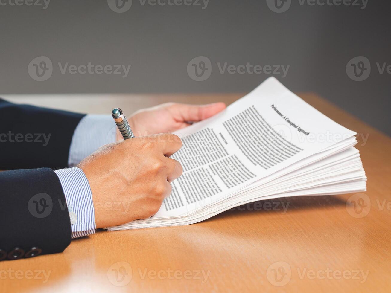 Hand of a businessman in a suit signing on lease contract or agreement while sitting in the office photo