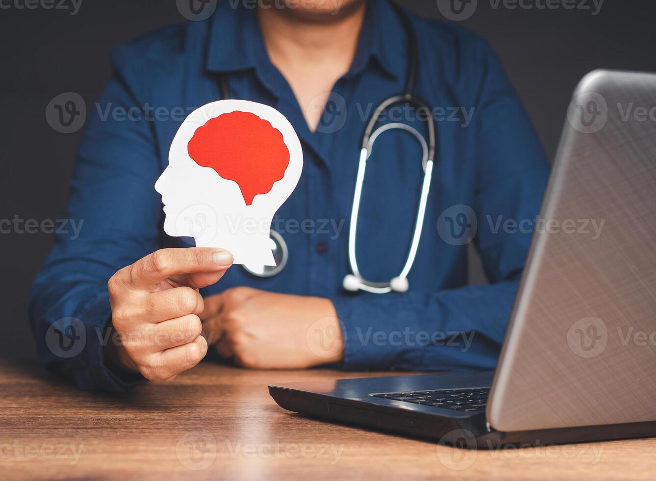 Doctor holding a white head made from paper with a red brain symbol while sitting in the hospital photo