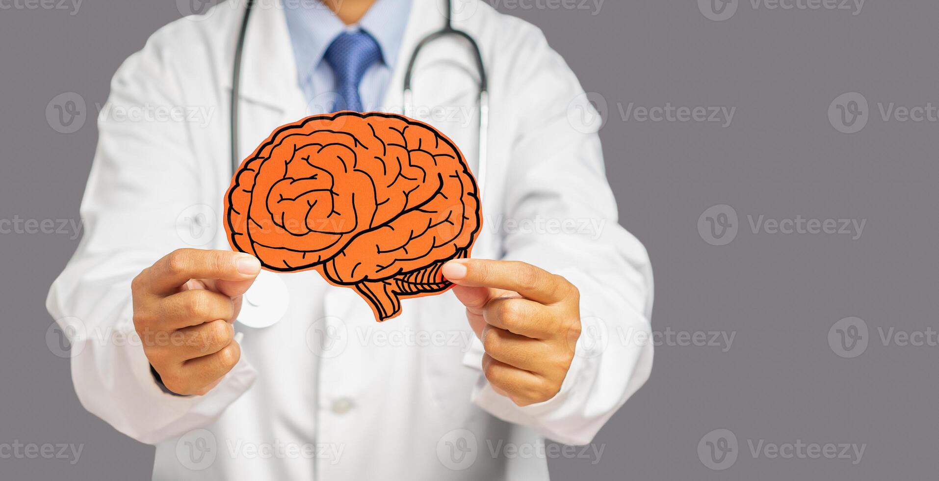 Doctor in uniform holding a white head with a red brain symbol while standing on a gray background photo