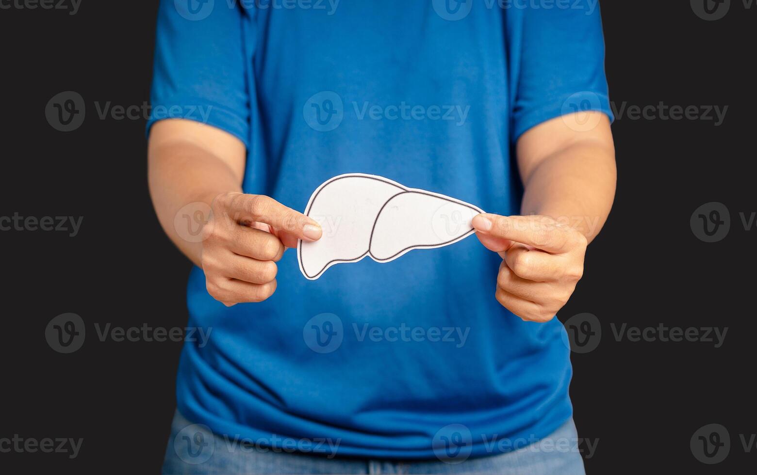 Hands holding a liver shape symbol made of paper while standing on a black background photo