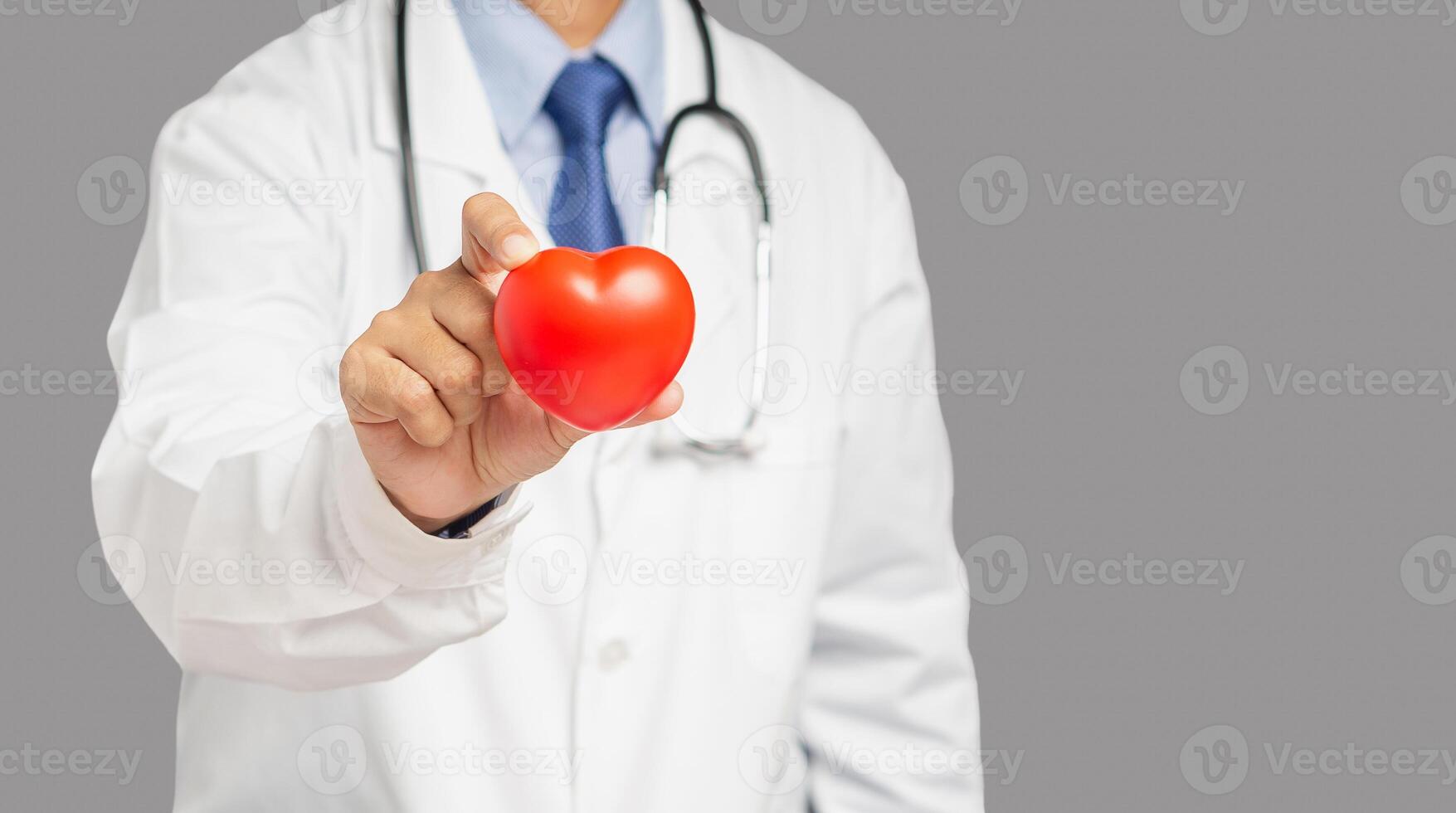 Cardiology concept. Close-up of hand doctor holding a red heart shape while standing in the hospital photo