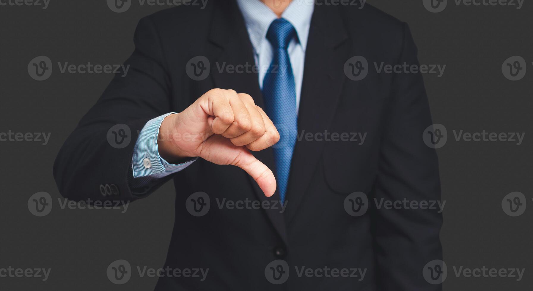 Negative concept. Close-up of a businessman's hand showing thumbs down while standing on a gray background photo