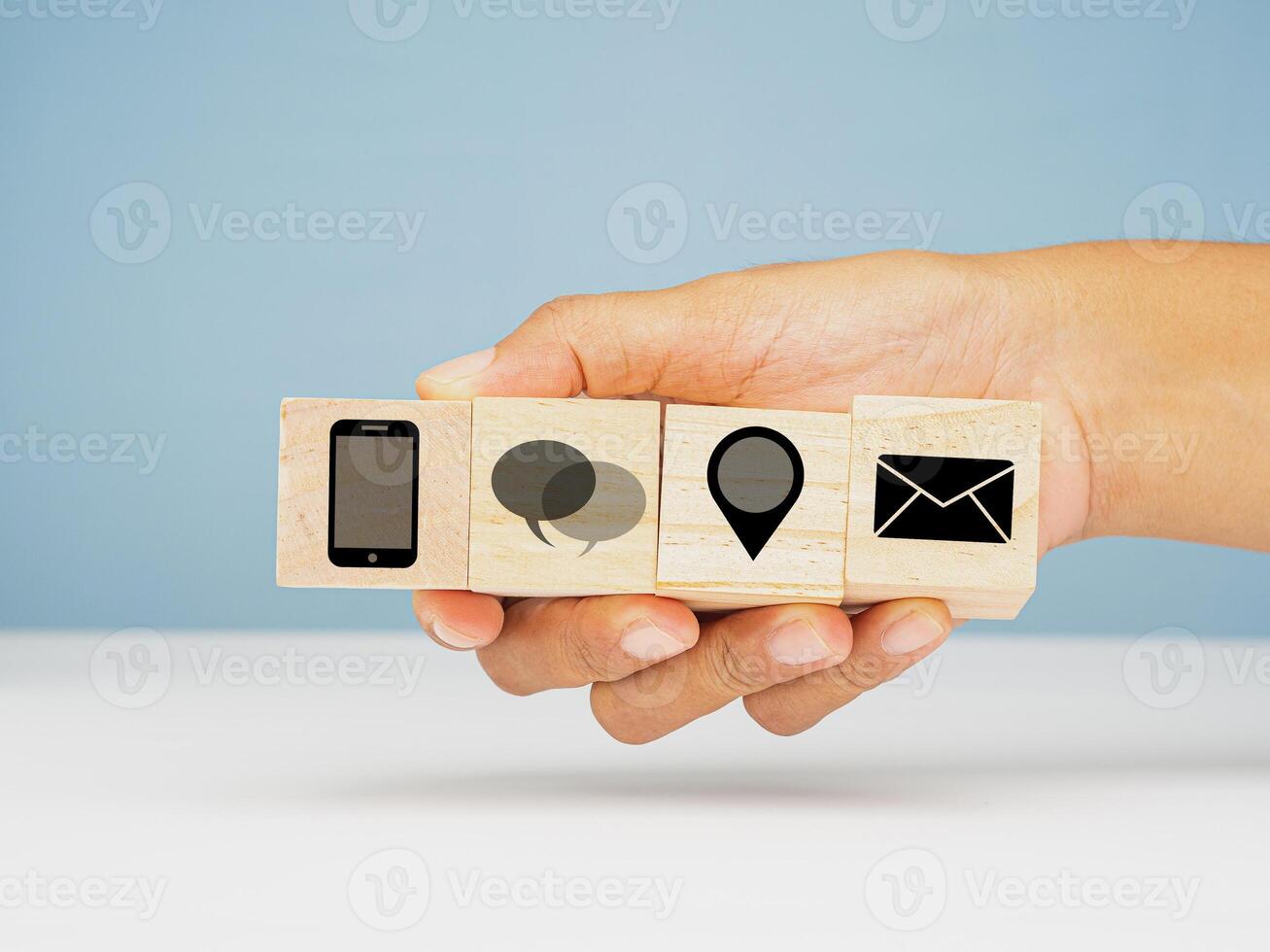 Contact us concept. Close-up of hand-holding wooden cubes with a symbol, smartphone, chat, location, and email icons. photo