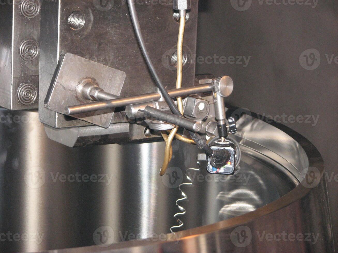 Close-up of precision industrial machinery with metal components, wires, and a sensor. Ideal for engineering, tech, or abstract backgrounds. photo